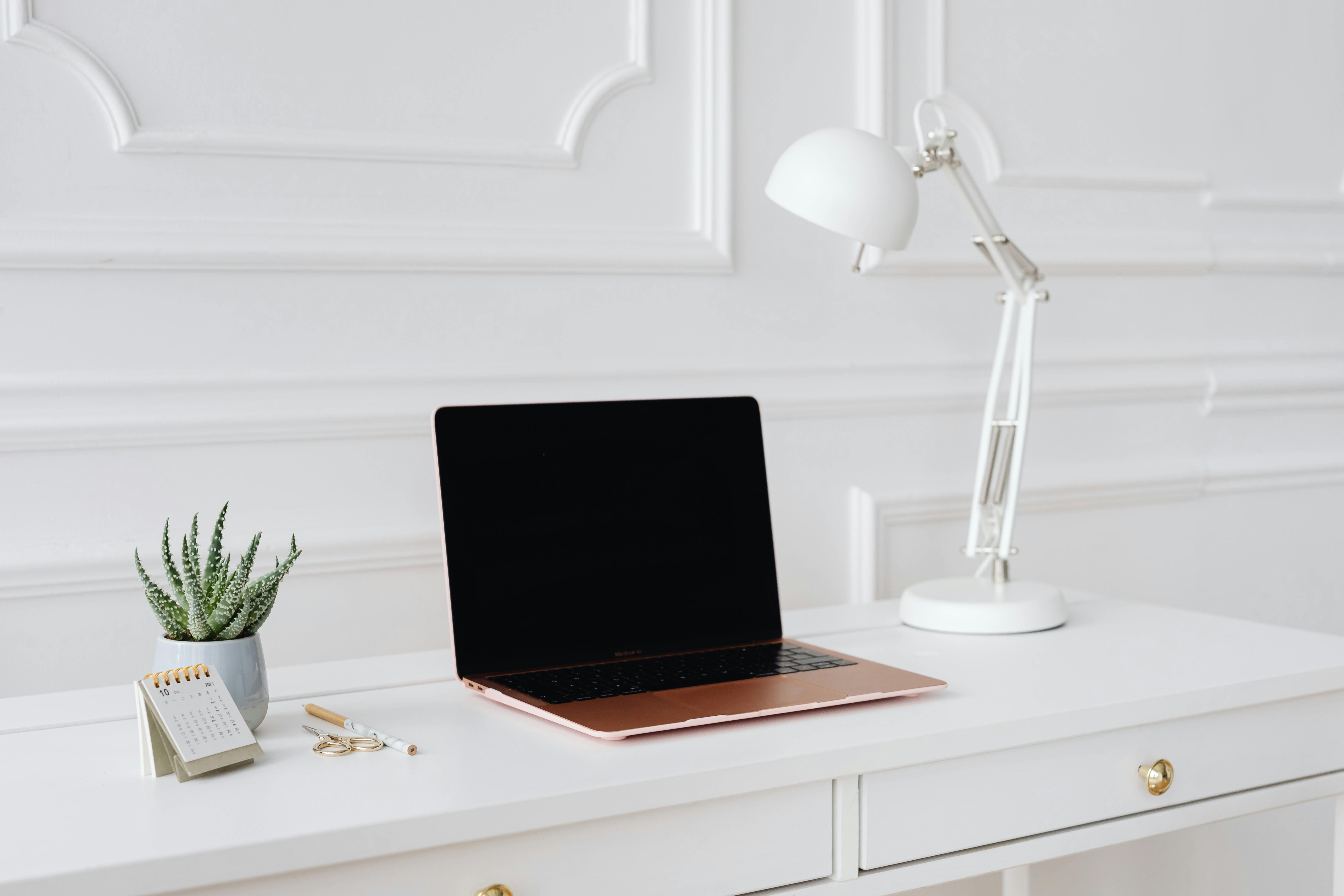 Minimalist white desk with a MacBook and desk lamp