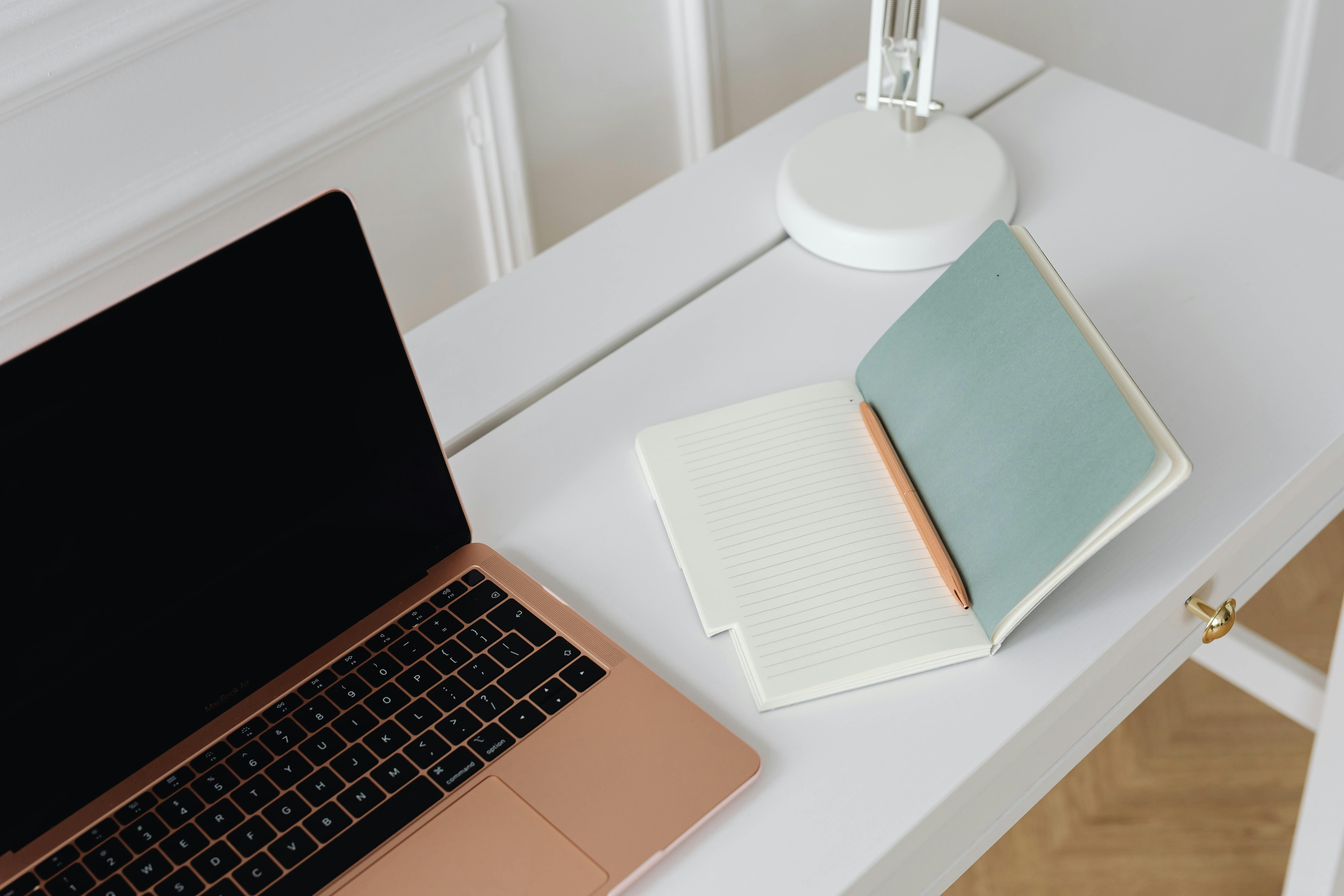 White desk with a MacBook and open notebook