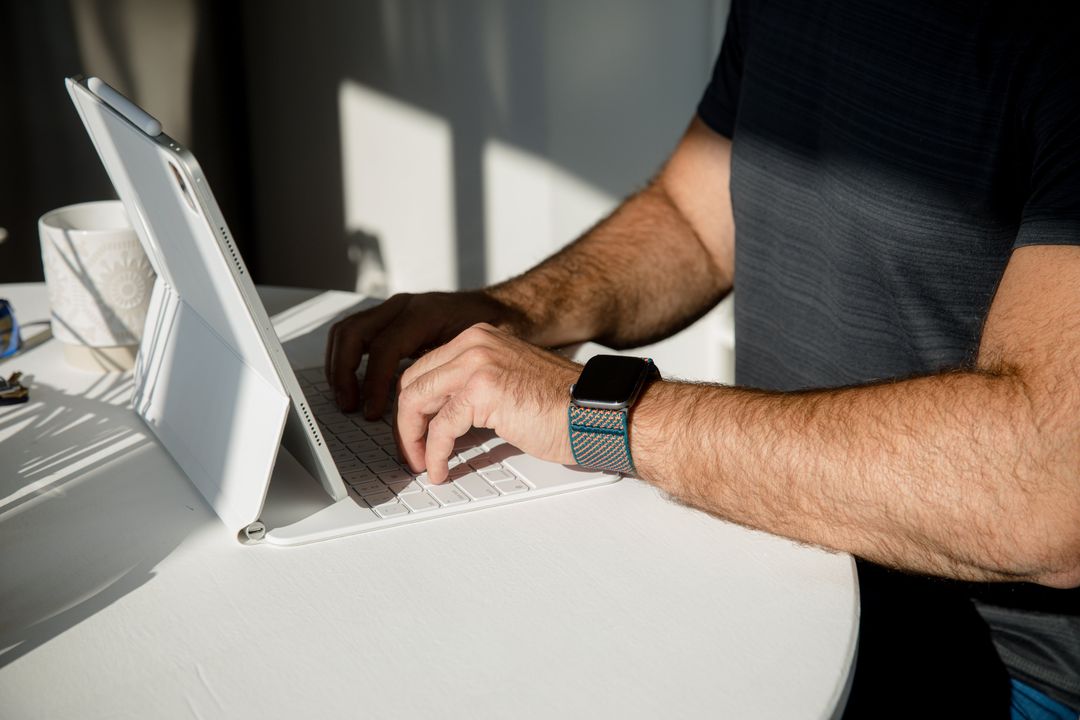 Person typing on a laptop while wearing a smartwatch